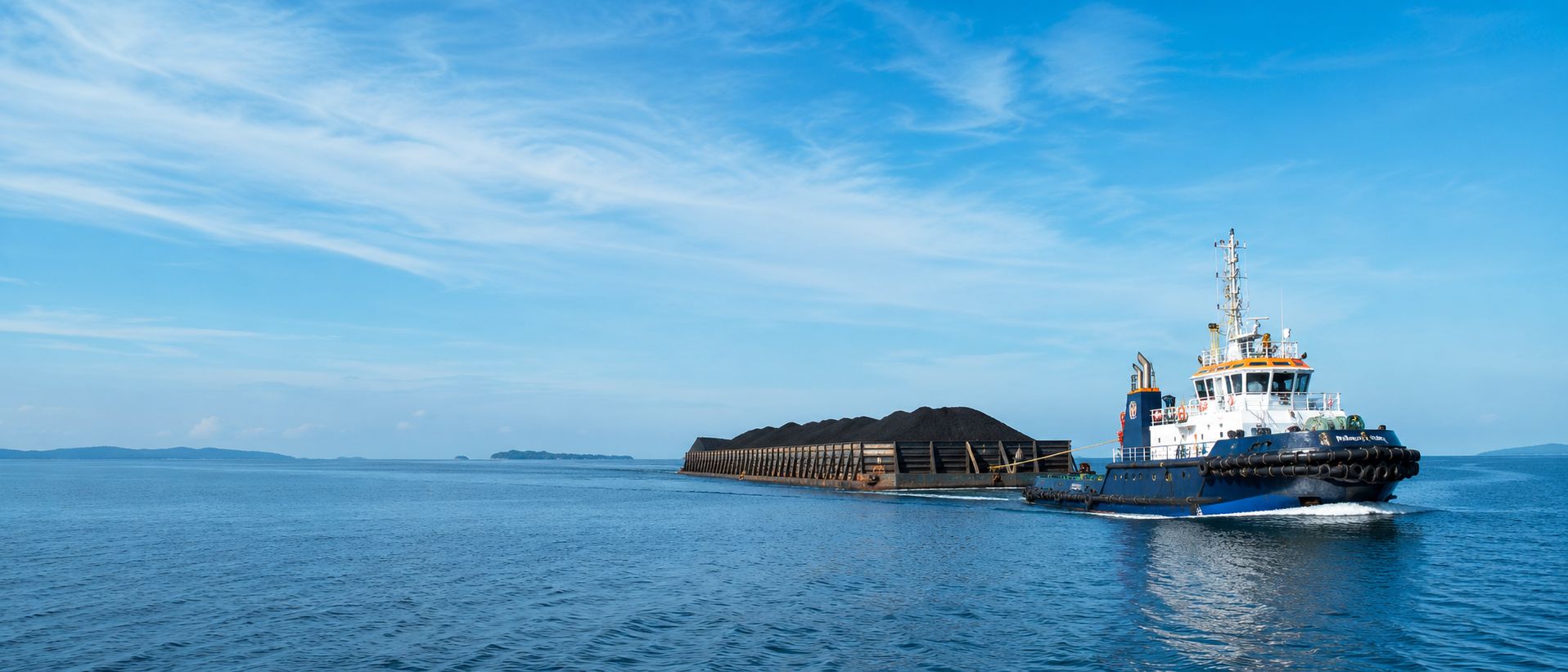 Tugboat towing a loaded bulk barge across Indonesian waters — PT Tiga Saka Samudra